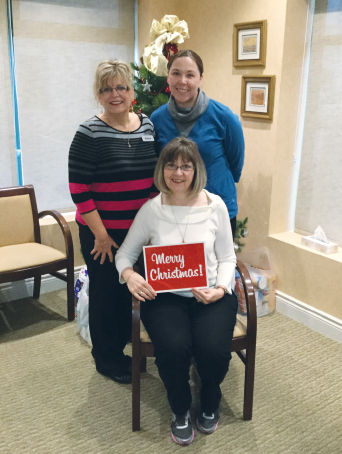 group of women with one holding a sign which reads Merry Christmas